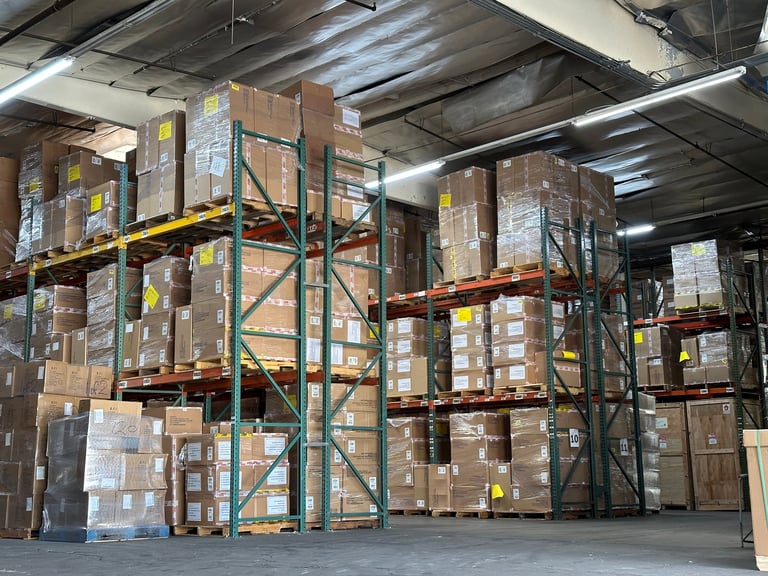 Industrial warehouse storage facility with tall pallet racks stacked with cardboard boxes under fluorescent ceiling lights